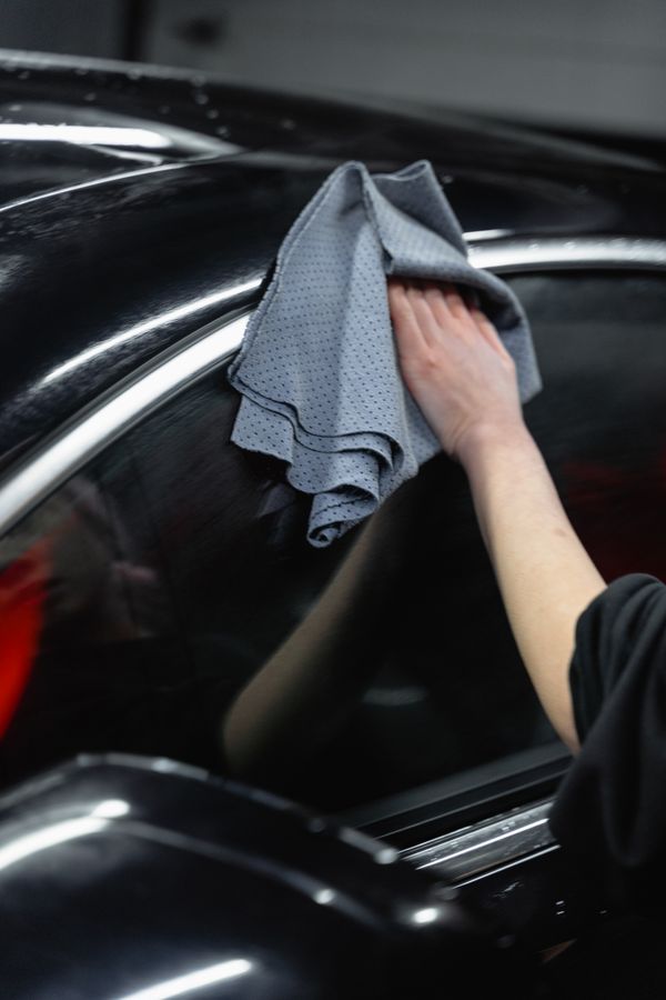 Glinto crew member wiping down a car's exterior with a microfiber cloth